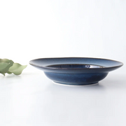 A side view of a Tojiki Tonya Orlo Series Pasta Plate, 24cm, highlighting the deep blue colour with a slightly raised textured rim.