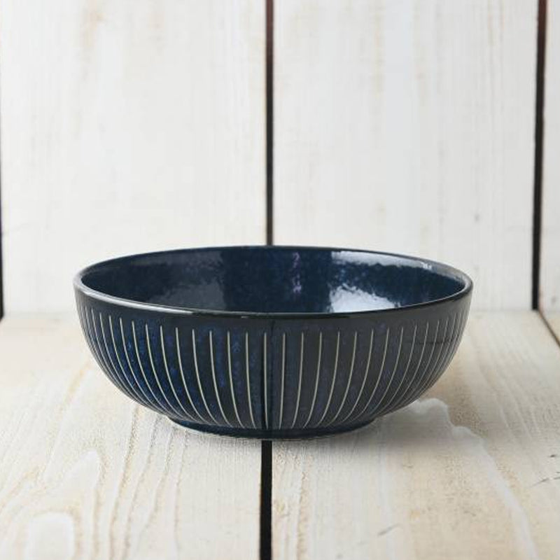 Side view of the Toki Takane Indigo Tokusa Bowl (20cm) on a white timber surface, showing the vertical stripe pattern