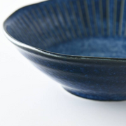 A detailed close-up of the Tokusa Indigo Bowl, showing the rich texture of the indigo glaze and the elegant pinstripe pattern.

