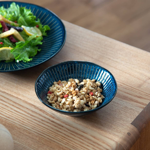 The Tokusa Indigo Bowl filled with granola, displayed on a wooden table as part of a matching tableware set.

