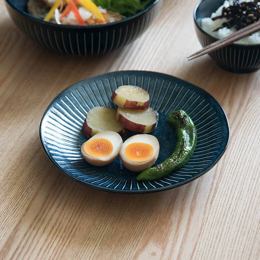 A Japanese-style meal served on the Tokusa Indigo Dinner Plate (20cm), featuring a soft-boiled egg, sweet potato, and pepper.

