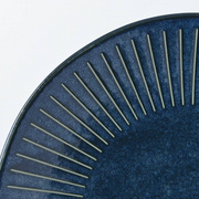 A close-up detail shot of the Tokusa Indigo Dinner Plate, focusing on the texture of the speckled glaze and the hand-painted feel of the white stripes.

