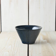 A close-up macro shot of the Tokusa Indigo Salad Bowl, highlighting the detailed vertical stripes and the rich, speckled indigo glaze.

