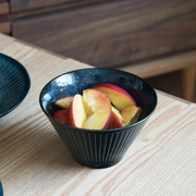 The Tokusa Indigo Salad Bowl (13cm) filled with fresh sliced peaches, sitting on a light wood table.








