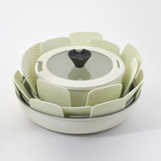 A stack of non-stick frying pans and a saucepan separated by light green Tortino cookware protectors to avoid surface damage.
