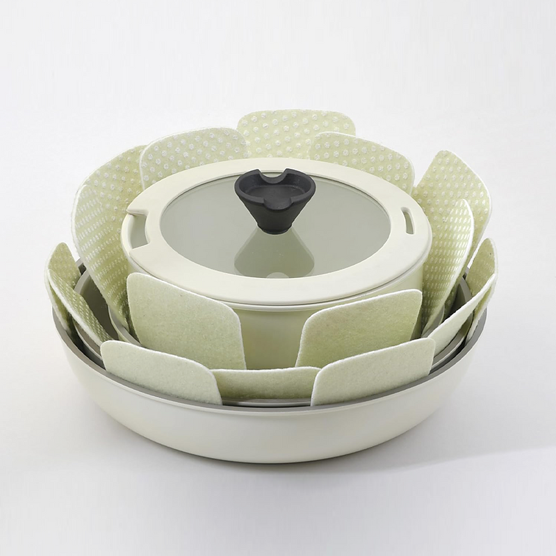 A stack of non-stick frying pans and a saucepan separated by light green Tortino cookware protectors to avoid surface damage.
