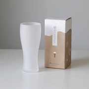 Toyo Sasaki Frosted Beer Glass in Use with Beer and Food – A frosted beer glass filled with beer, featuring a thick foamy head, placed next to a meal with chopsticks and a beer bottle in the background.

