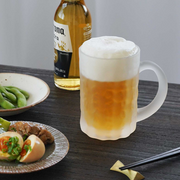 Toyo Sasaki Frosted Beer Mug in Use with Beer and Food – A frosted beer mug filled with golden beer and a thick foamy head, placed beside Japanese appetizers, with a beer bottle in the background.

