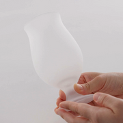 Hands holding a frosted tulip beer glass, showcasing its smooth texture and ergonomic design.




