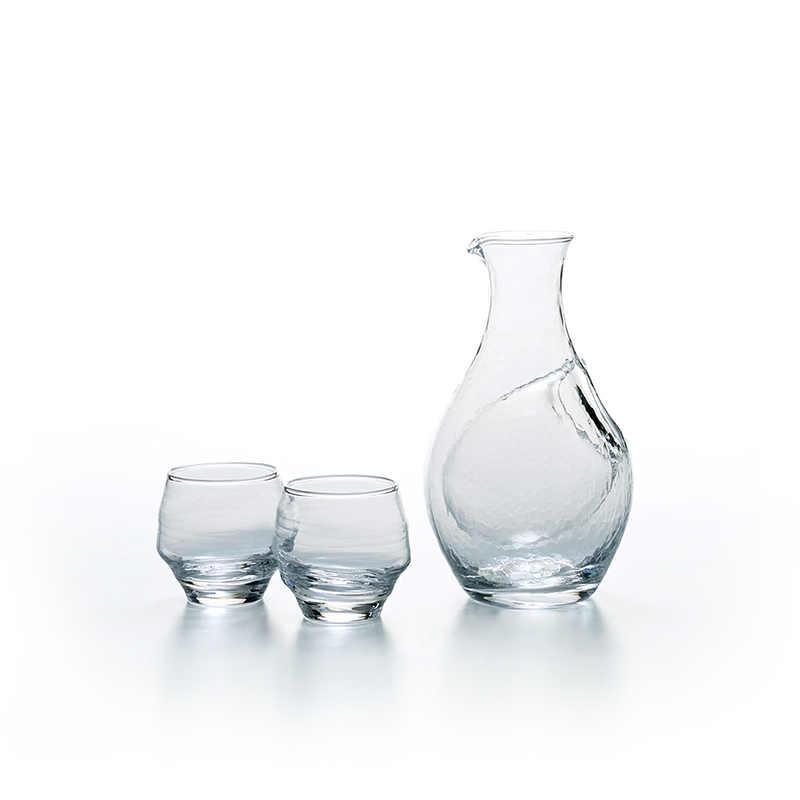 The Toyo Sasaki handmade clear glass sake set, featuring a rippled texture carafe and two matching small cups, shown together against a white background.
