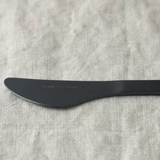 Close-up of a Tsubame Sanjo matte black dessert knife highlighting the sleek design and branding
