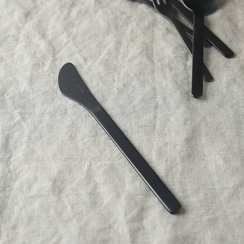 Matte black dessert knife from Tsubame Sanjo, lying on a textured linen tablecloth
