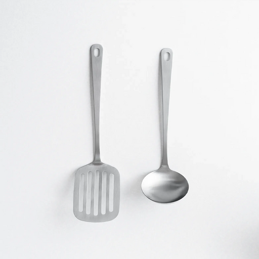 Two matte stainless steel kitchen utensils, a slotted turner and a soup ladle, arranged side-by-side on a white background.