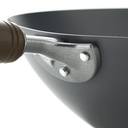 Black wok with a wooden handle on a white background, angled view showing the rounded interior and sturdy handle.