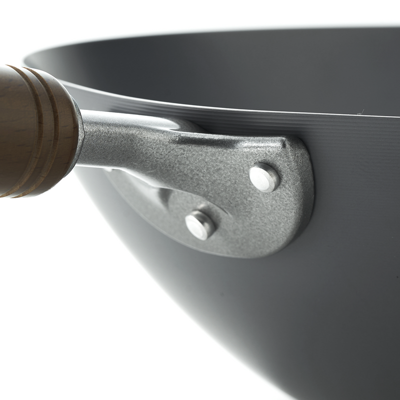 Black wok with a wooden handle on a white background, angled view showing the rounded interior and sturdy handle.