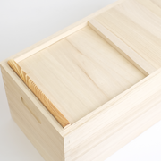 Traditional Japanese paulownia (kiri) wood rice storage box with sliding lid partially open, showing natural pale grain and carved side handle