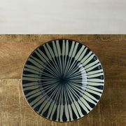 Top view of a Japanese bowl with a radial Tokusa pattern in black and white, displayed on a wooden surface.