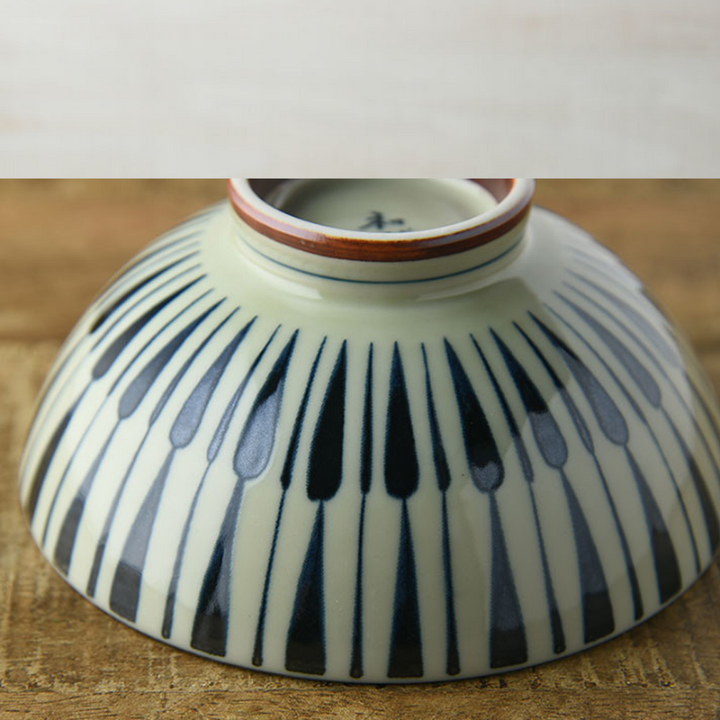 Underside view of a Japanese bowl showcasing a continuous Tokusa stripe pattern along its curvature.