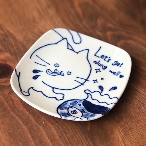 Square ceramic plate featuring a playful cat illustration in indigo blue with the text 'Let’s get along well' written in a whimsical font, placed on a wooden surface.