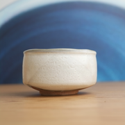 A side profile of the Yamaman Kohiki matcha bowl, highlighting the contrast between the soft, textured white glaze and the unglazed clay foot.