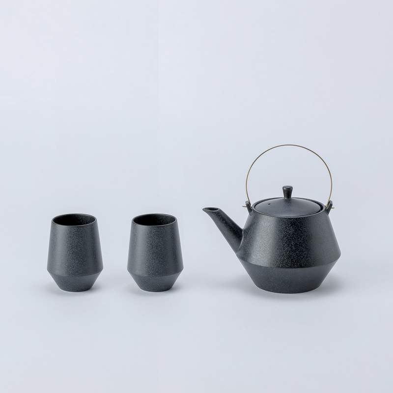 amatsu Frustum Japanese teapot with brass handle and two matching black teacups displayed on a white background.