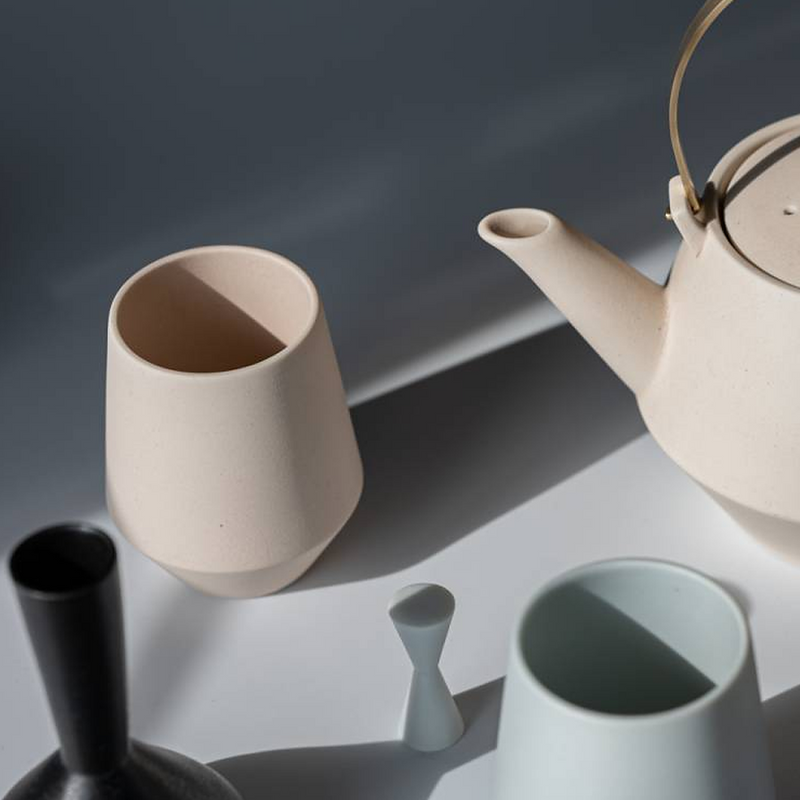 Top view of Yamatsu Frustum teapot and teacups in pink, blue, and black under natural lighting.


