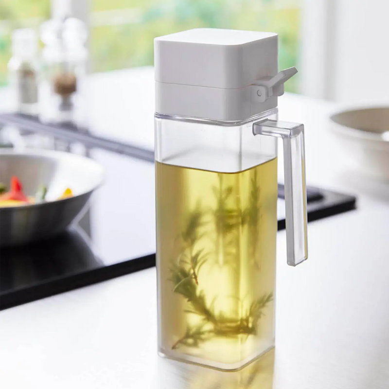 The white Yamazaki Tower condiment dispenser filled with rosemary-infused olive oil on a modern kitchen counter.


