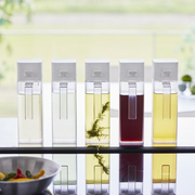 A set of five Yamazaki Tower condiment dispensers neatly lined up, showing their use for various oils and sauces.

