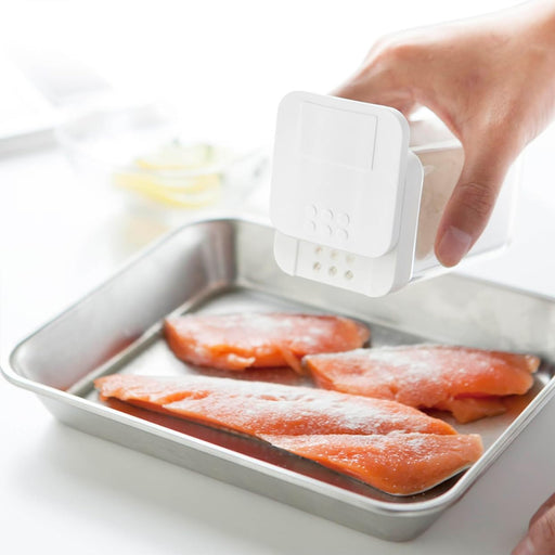 Yamazaki Tower flour and spice bottle in white sprinkling flour over salmon fillets on a tray