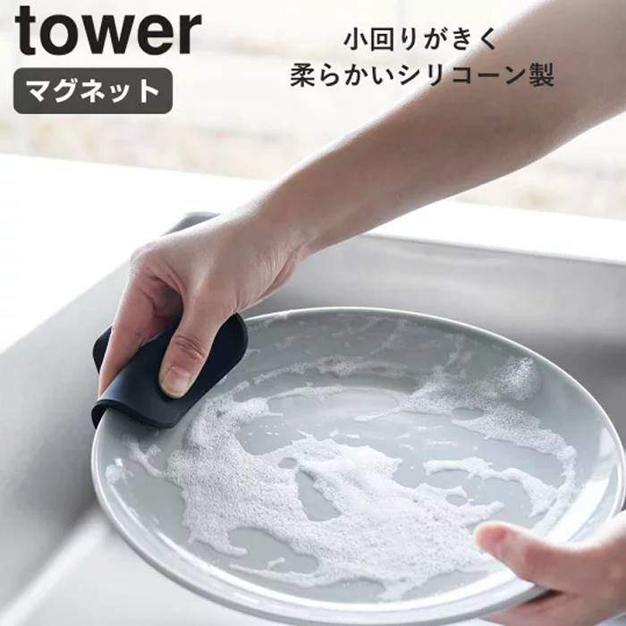 Hand holding the flexible Yamazaki Tower Series silicone sponge while cleaning a plate with soap suds.
