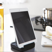 Yamazaki Tower Series Stand holding a white tablet, set on a kitchen countertop with a cutting board and onion.
