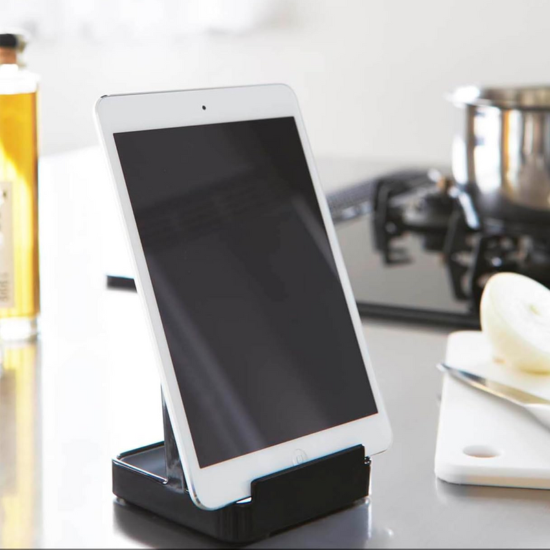 Yamazaki Tower Series Stand holding a white tablet, set on a kitchen countertop with a cutting board and onion.
