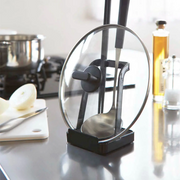 Yamazaki Tower Stand holding a glass pot lid and ladle, placed beside kitchen essentials on a countertop.
