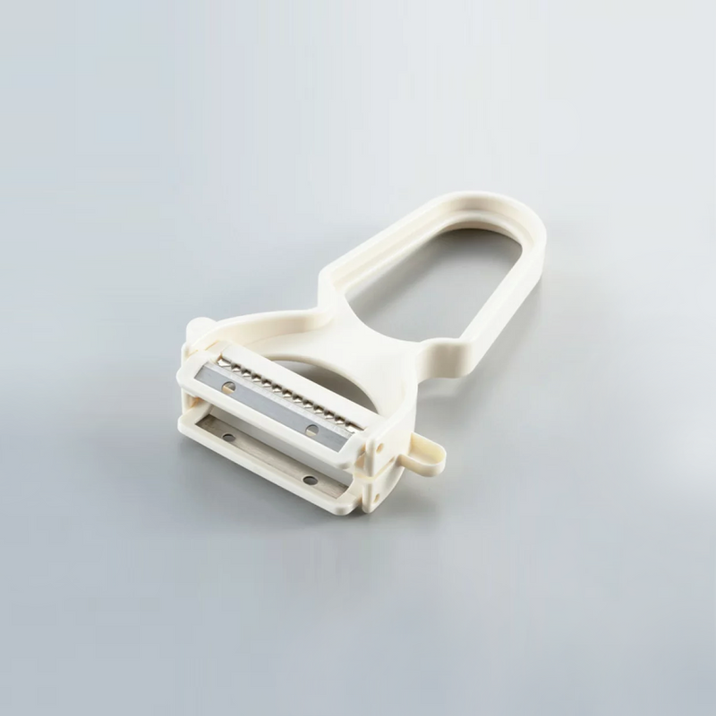A white Yoshikawa double-blade peeler featuring both straight and julienne stainless steel blades on a grey background.