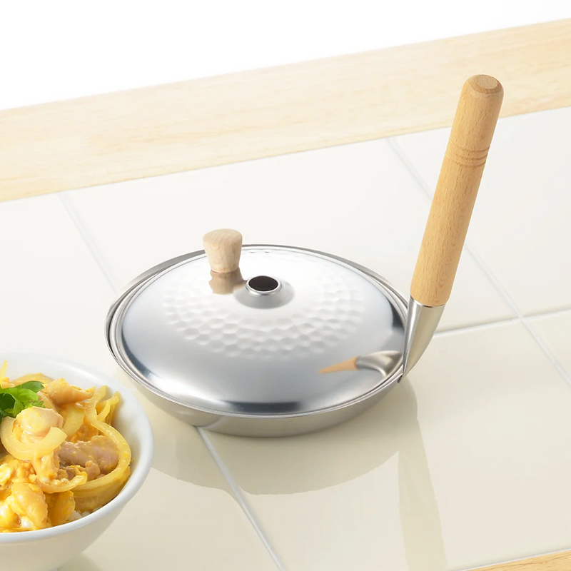 A product image of the Yoshikawa 16cm Oyakodon Pan, showing its unique vertical wooden handle and matching stainless steel lid.