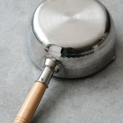 Metallic cooking pot with wooden handle on gray background