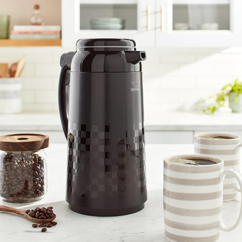 Zojirushi 1L black thermal pot in a kitchen setting with coffee mugs and a jar of beans.

