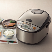 The Zojirushi MICOM Logic Rice Cooker 5.5 Cups shown as part of a traditional Japanese meal with grilled fish and fresh rice.

