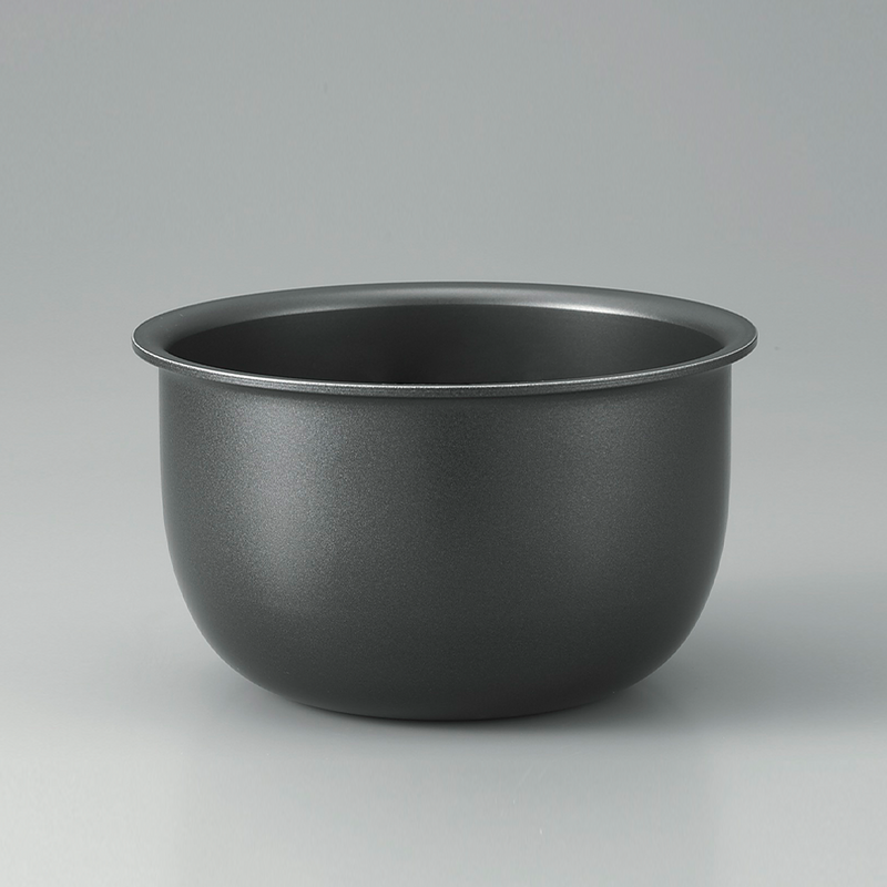 The thick, black, non-stick inner cooking pot of the Zojirushi Micom Rice Cooker shown against a grey background.


