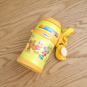 Yellow children's thermos with cartoon characters on a wooden surface