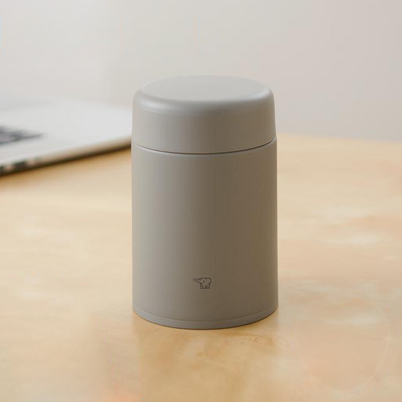 A matte grey Zojirushi SW-KA52 vacuum insulated food jar with a seamless one-piece lid sitting on a light wooden table.