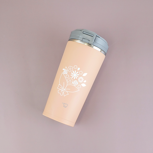 A cinnamon beige Zojirushi SX-KA30 vacuum insulated tumbler with a white flower bouquet design and a grey flip lid lying diagonally on a mauve background.