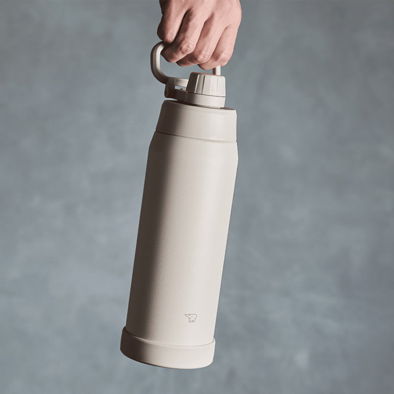 Zojirushi SD-KA60-HM 600ml vacuum insulated sport flask in Misty Gray, held by the folding carry handle