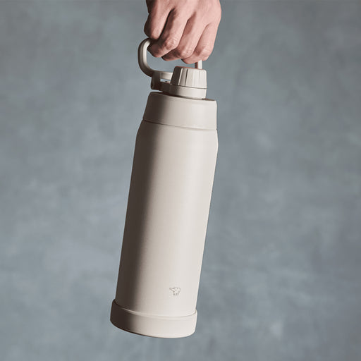 Zojirushi SD-KA60-HM 600ml vacuum insulated sport flask in Misty Gray, held by the folding carry handle