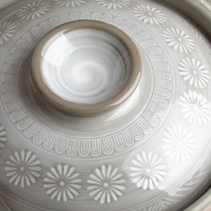 Close-up of the lid of the Ginpo Hana Mishima Mini Donabe Japanese Clay Pot, featuring a white floral pattern on a grey background with a circular handle in the centre.