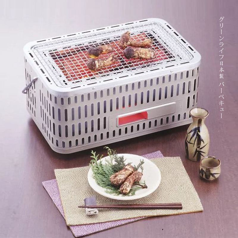 Close-up of skewered meats grilling on the Green Life Japanese konro grill with visible smoke.

