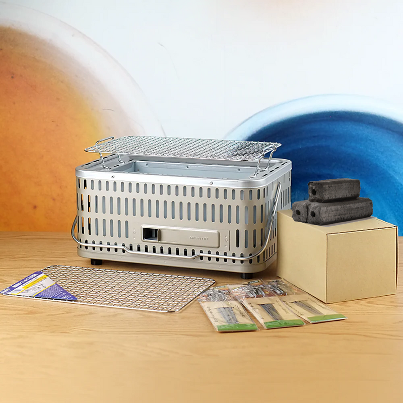 All the components of the Green Life Stainless Steel Konro Grill Starter Set, including the grill, two grill meshes, binchotan charcoal, and skewers.