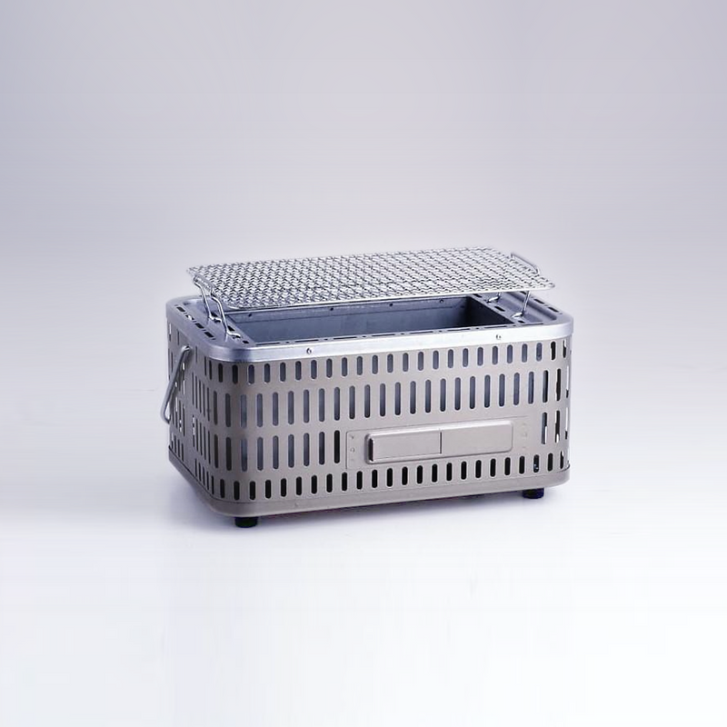 A product image of the Green Life Stainless Steel Konro Grill, showing its modern perforated steel body and included grill mesh.


