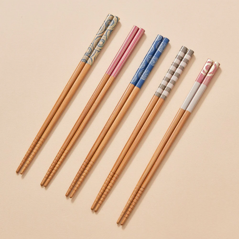 A studio photo of the Ishida Tennen Zai chopstick set, showing five pairs of natural bamboo chopsticks with assorted colourful patterned handles, displayed in their retail packaging.