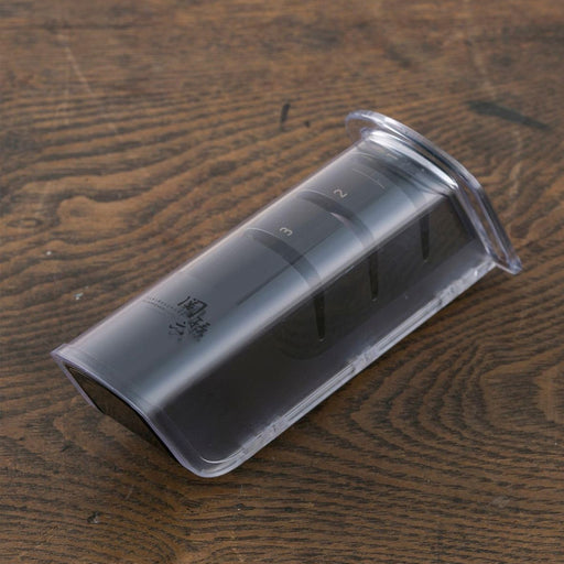 The Kai Seki Magoroku Diamond and Ceramic Knife Sharpener shown with its transparent protective cover on, resting on a dark wooden surface.
